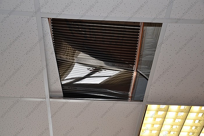 Пленочный электронагреватель разложен на каркасе потолка Армстронг в обход освещения